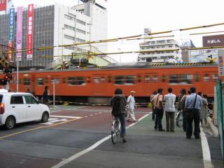 武蔵小金井駅東側にあった小金井街道踏切。オレンジ色の201系も高架化とともに消えた。