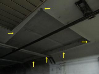 切り取られた天井を拡大。四隅にはコア抜きをした時にできたと思われる丸い断面が見える。（矢印の先）